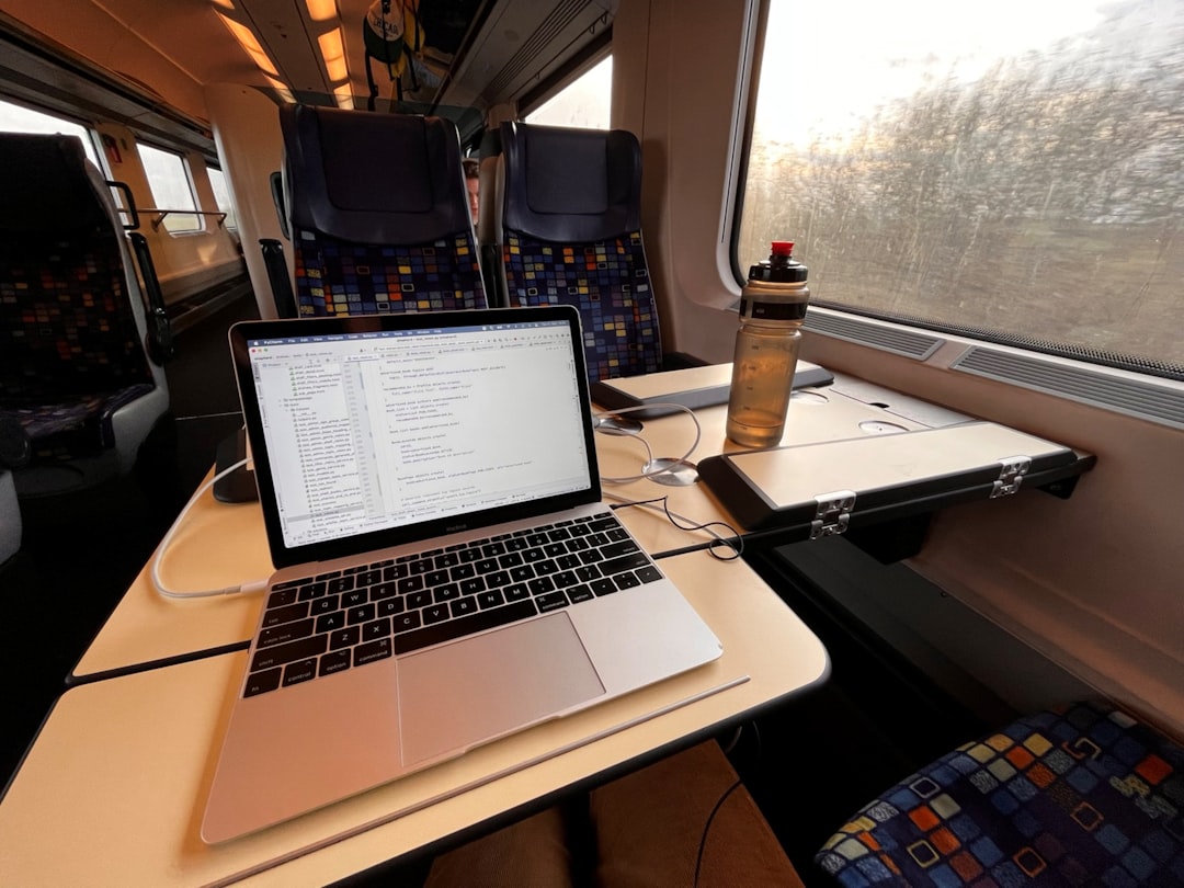 man work at train with macbook
